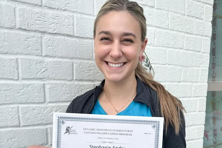 Paige Boscareno holding a physical therapy certification at Pediatric Therapy Solutions.